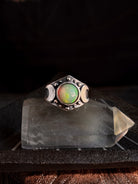 Silver ring with a colorful gemstone on a dark background
