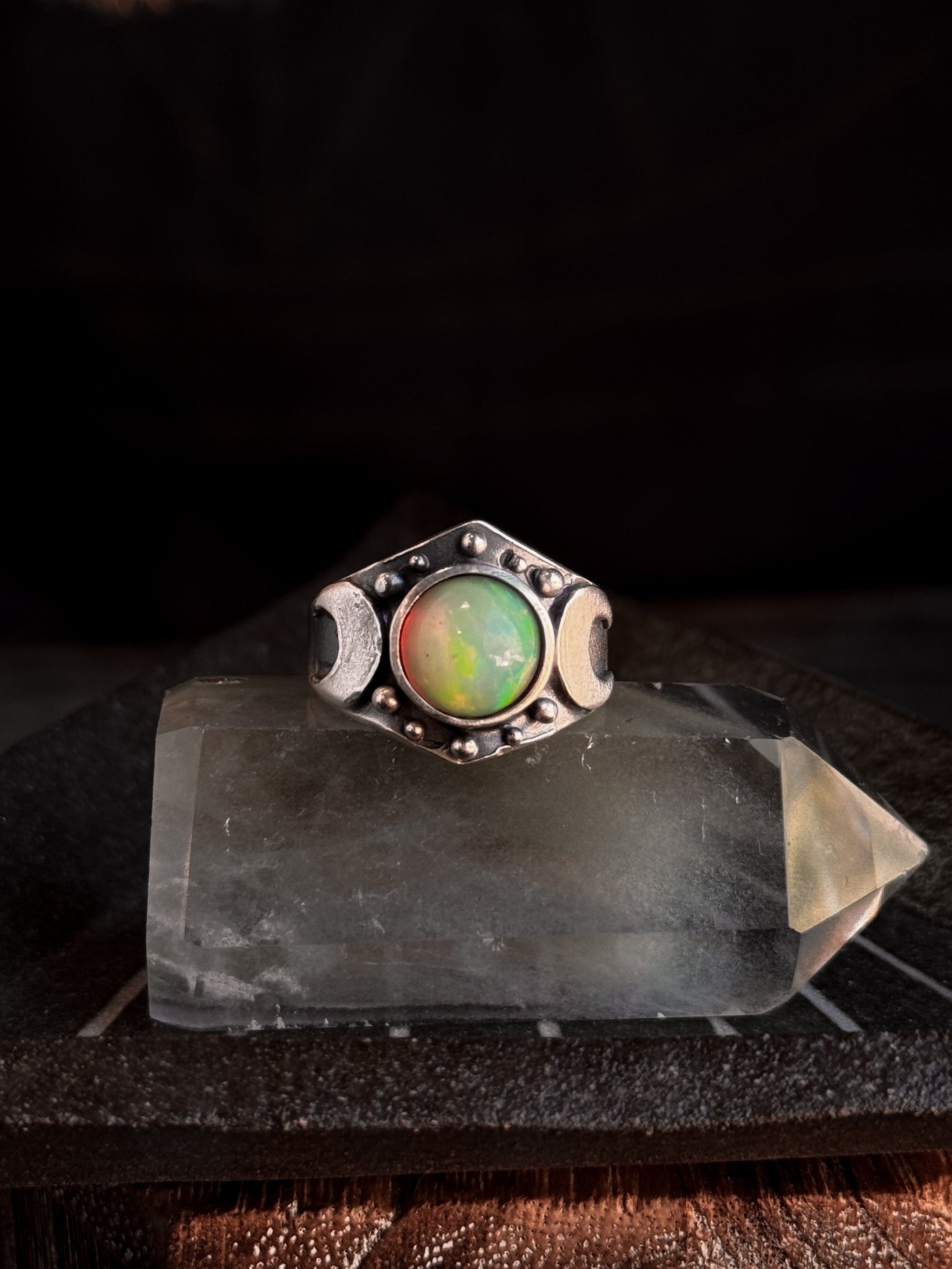 Silver ring with a colorful gemstone on a dark background